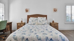 Ein Schlafzimmer mit einem großen Bett, zwei Nachttischen, einem Sessel und Bildern an den Wänden.