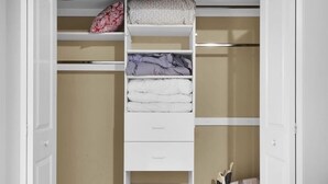 Ein begehbarer Kleiderschrank mit offenen Türen, der mehrere Regale und Schubladen zur Aufbewahrung bietet.