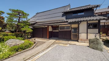 A traditional Japanese house with a tiled roof, wooden doors, and a stone pathway leading to the entrance.