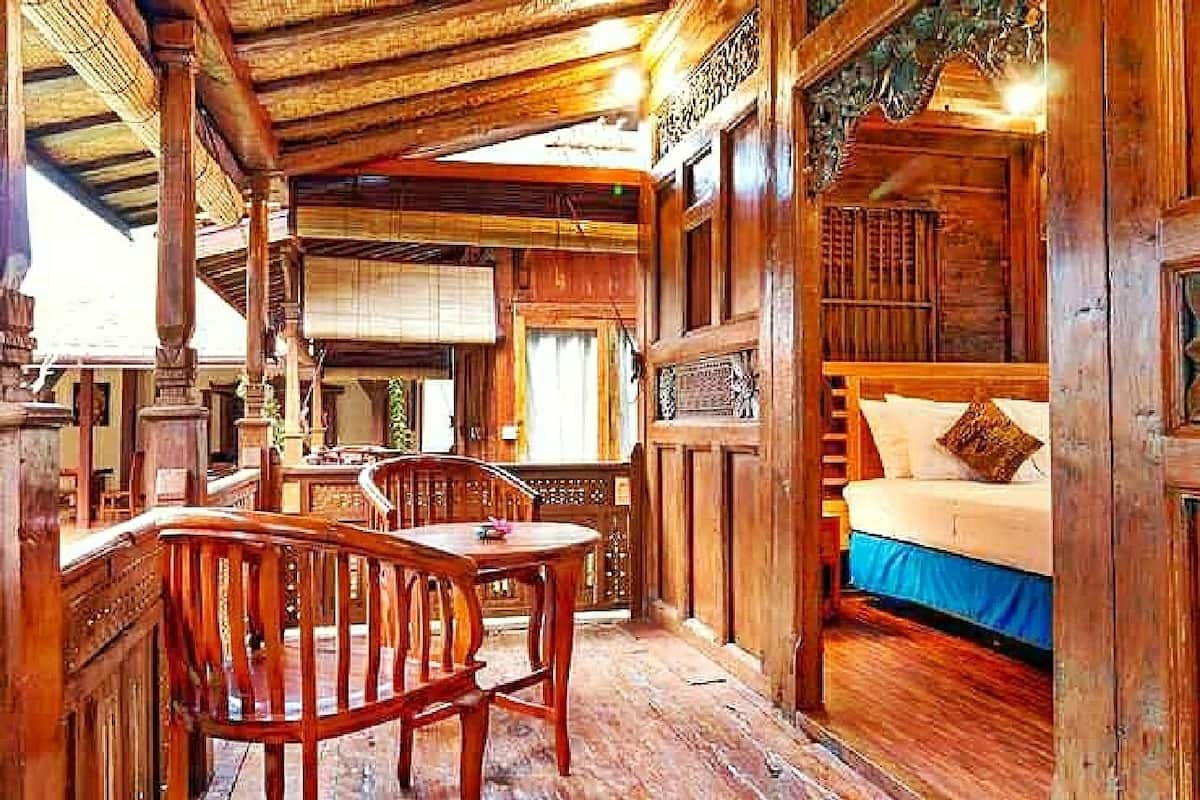 Ein Holzblockhaus-Innenraum mit einem Bett, einem Esstisch mit Stühlen und einem Balkon.