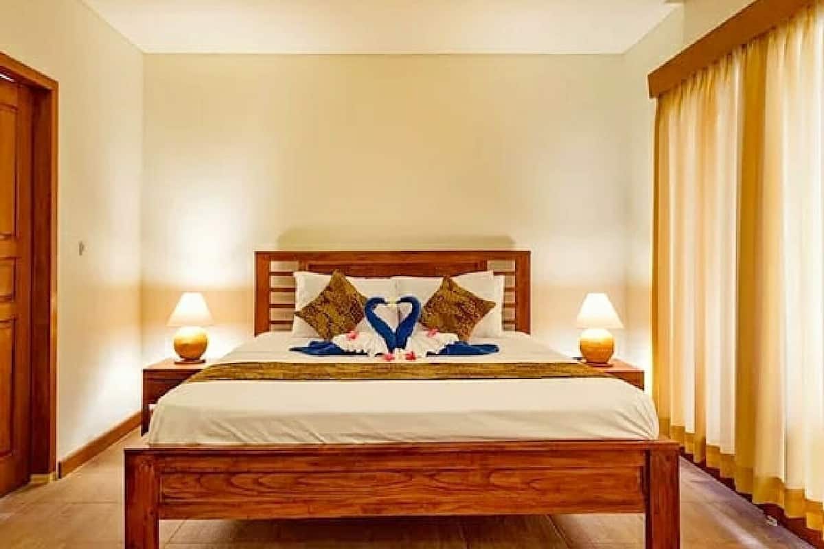 Ein Hotelzimmer mit einem hölzernen Bett, zwei Nachttischlampen und einem Kopfteil mit herzförmigen Kissen.