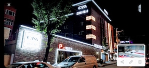 Un hotel con un llamativo letrero 'CASY', una señal de estacionamiento y un letrero 'LUXUE HOTEL'.