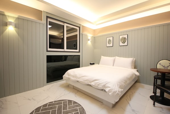 Un dormitorio moderno con cama, armario empotrado, una mesa redonda y dos cuadros en la pared.