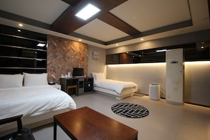 Una habitación de hotel moderna con dos camas, un escritorio, una silla, una mesita y un refrigerador.