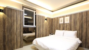 Une chambre à coucher avec un grand lit, des murs recouverts de panneaux de bois, une table de chevet et une commode.