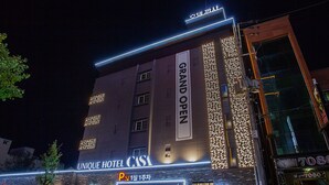 Un hôtel avec une enseigne indiquant « Grande ouverture », une autre indiquant « Hôtel unique » et un panneau « P » signalant un espace de stationnement.