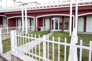 A building with a white fence, a stone pathway, and a small garden area.