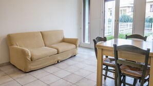A room with a beige sofa, a wooden dining table, and chairs. - S010 - Sirolo, new three-room apartment with garden (Sirolo)