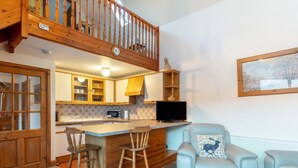 Una cocina acogedora con armarios de madera, una barra y un comedor con una silla azul claro.