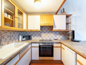 A compact kitchen with wooden cabinets, a microwave, a stove, and a dishwasher.