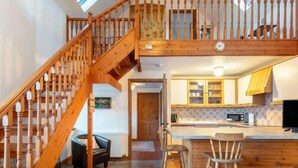 Una cocina amplia con armarios de madera, una isla central y una zona de comedor con taburetes.