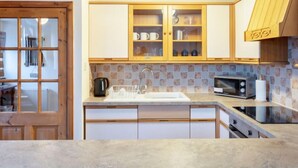 Una cocina moderna con armarios de madera, un microondas integrado y un lavamanos.