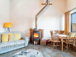 A cozy living room with a sofa, a table with chairs, a fireplace, and a lamp.