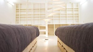 Una camera moderna e minimalista con due letti, una scala a chiocciola e scaffalature integrate.