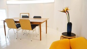 Un'area pranzo moderna con un tavolo e sedie in legno, un vaso con una pianta e un divano giallo brillante.