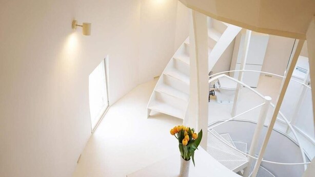 Un interno moderno con una scala a chiocciola, un vaso con fiori e un design minimalista.