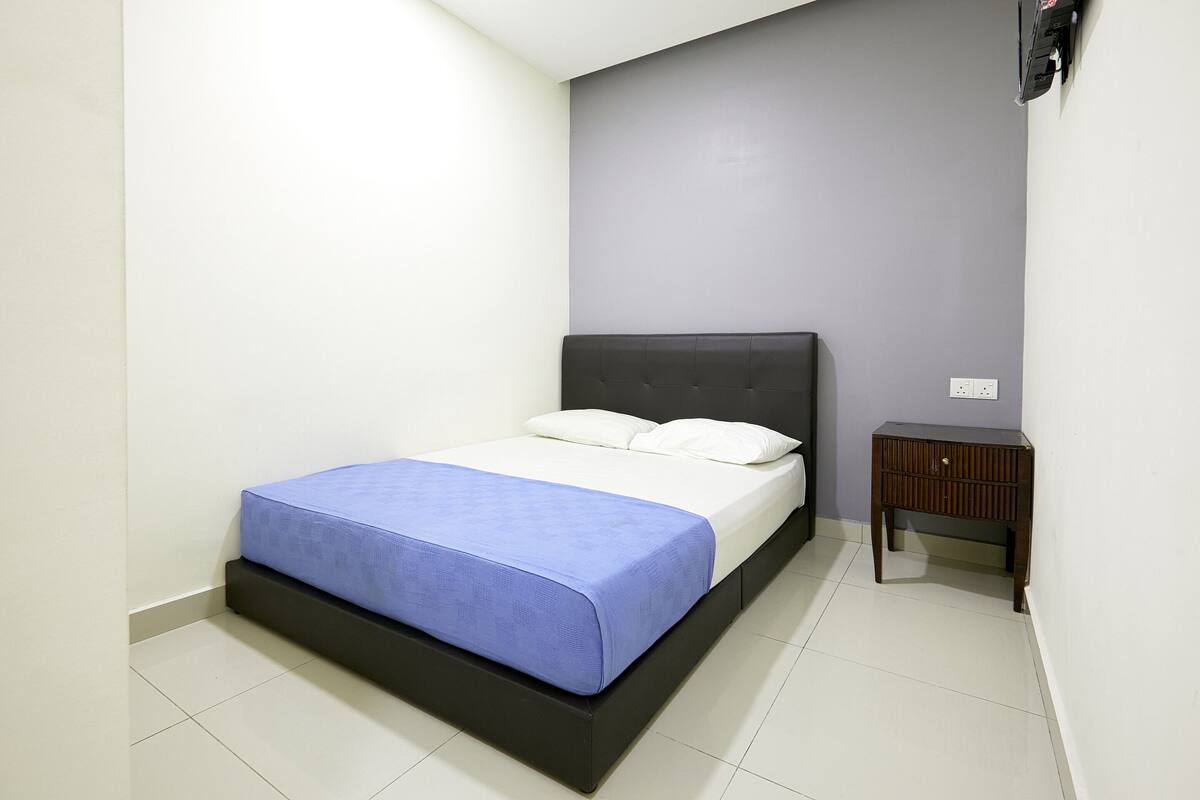 A bedroom with a bed, a nightstand, and a wall-mounted TV.