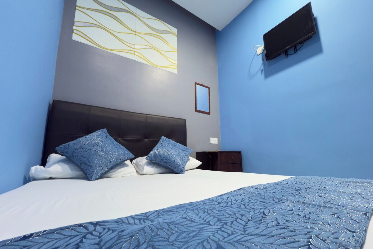 A neatly made bed with a patterned bedspread, a headboard, and two decorative pillows.