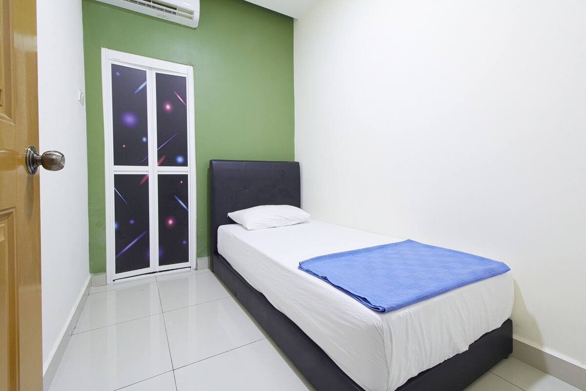 A bedroom with a bed, a window with a view of the night sky, a door, and a green wall.