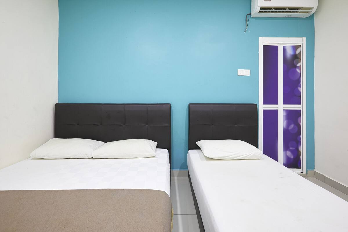 Two single beds with headboards, a blue wall, and a door with a purple glass panel.
