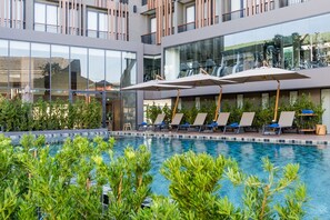 Een buitenzwembad, parasols bij het zwembad en ligstoelen