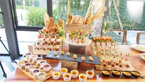 A table with various food and drink items, including bread, cheese, and small dishes. - The Teak Hotel (Mae Sot)