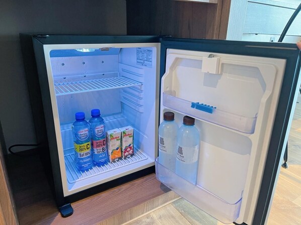 An open refrigerator with water bottles, cartons, and a milk carton.