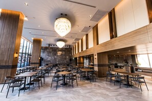 Un restaurant spacieux avec de hauts plafonds, de grands lustres et un décor intérieur moderne.