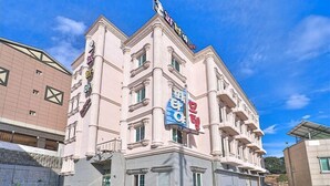 Un edificio rosa de varios pisos con un letrero llamativo en la parte superior.