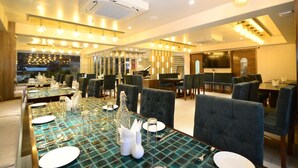 A restaurant with a long table set for dining, multiple seating areas, and a modern interior design. - Everland Wish - A Luxury Boutique Hotel (Jaipur)