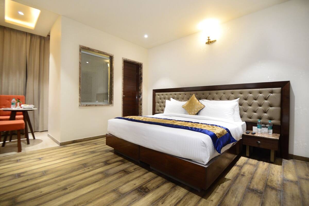 Ein Hotelzimmer mit einem großen Bett, einem Nachttisch, einem Sessel und einem Fenster.