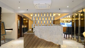 A modern reception area with a marble counter, wooden paneling, and a seating area with chairs. - Everland Wish - A Luxury Boutique Hotel (Jaipur)