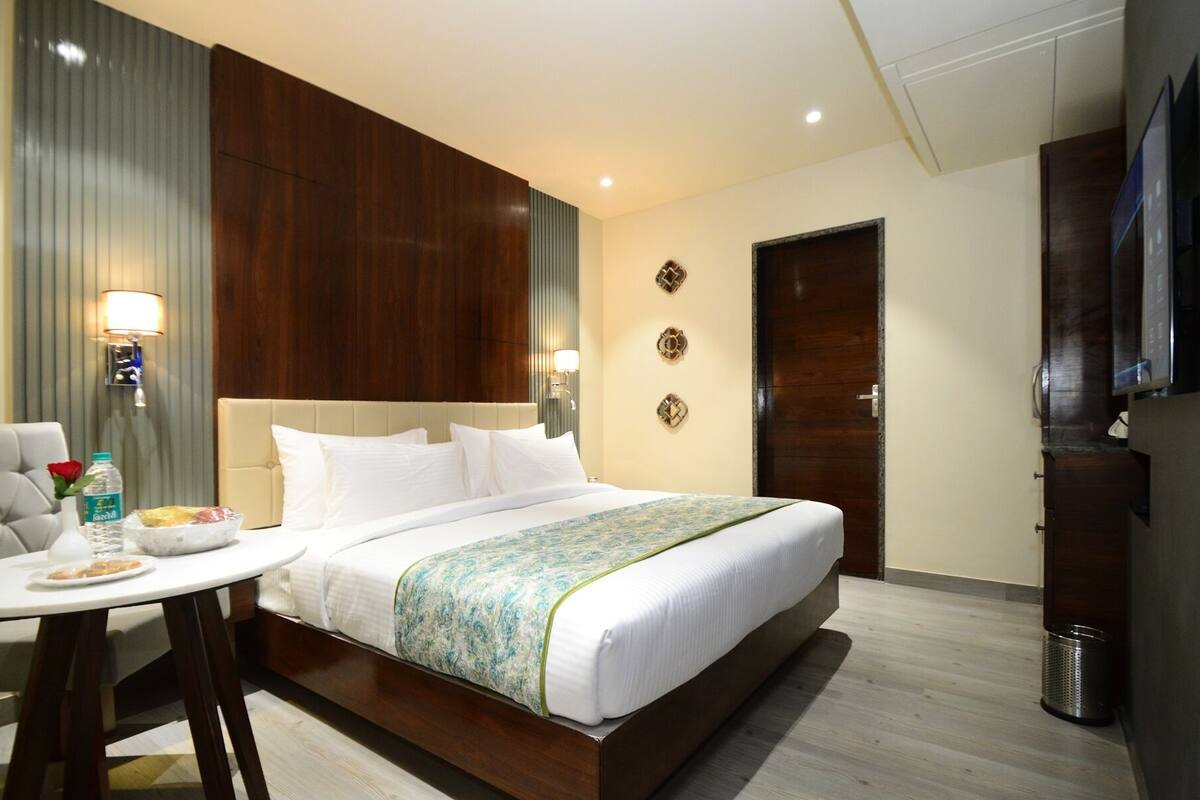 Ein Hotelzimmer mit einem großen Bett, einem kleinen Tisch mit Frühstücksangeboten, einem Fernseher und einem Mülleimer.