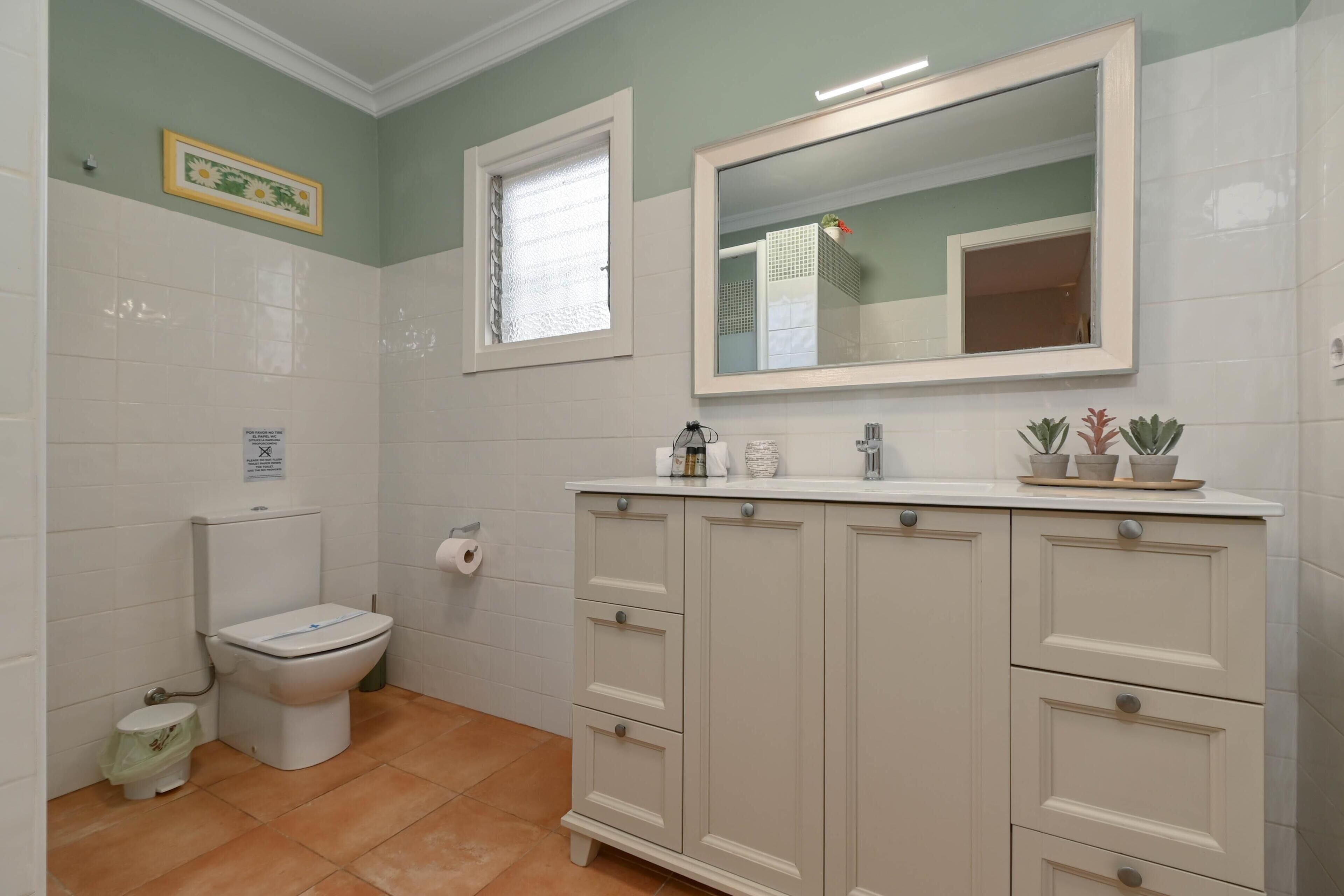 Ein Badezimmer mit Toilette, Waschbecken, Spiegel und Schränken.