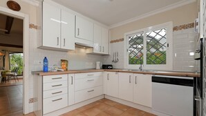 A modern kitchen with white cabinets, a built-in dishwasher, and a window with a view of greenery. - Ginjoler 4 pax - Javea, Costa Blanca (Javea)