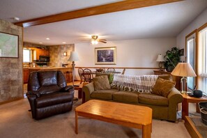 Ein Wohnzimmer mit Ledersessel, Couch, Holz-Couchtisch und einem Essbereich mit Tisch und Stühlen.