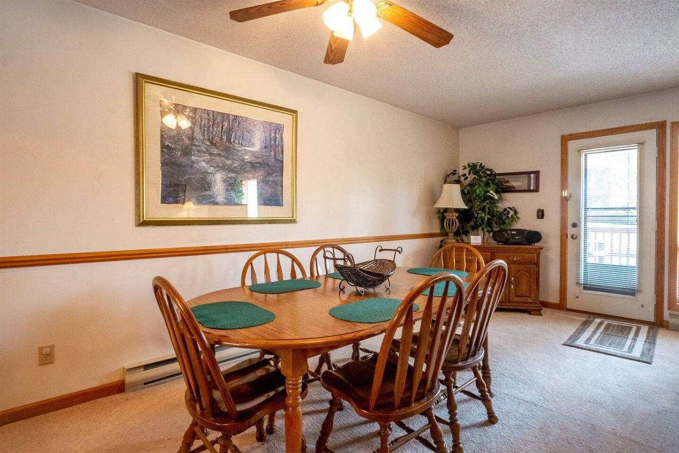 A dining area with a wooden table, chairs, and a ceiling fan.