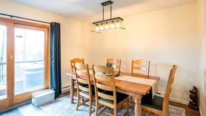 A dining area with a wooden table and chairs, a hanging light fixture, and a sliding glass door leading to an outdoor deck. - Bear Hug Inn - 74 Lower Lane

Bear Hug Inn - Pet Friendly, Wood Fireplace (Davis)
