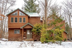 Una baita di legno a due piani con tetto verde, un portico anteriore e un cartello con il numero 10.