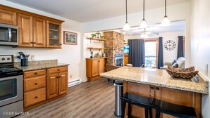 A kitchen with wooden cabinets, granite countertops, a built-in oven, and a stone accent wall. - Bear Hug Inn - 74 Lower Lane

Bear Hug Inn - Pet Friendly, Wood Fireplace (Davis)