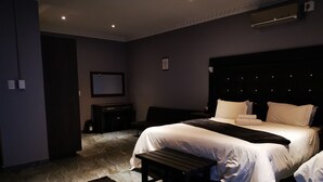 A modern bedroom with a large bed, a bench, and a TV on the wall. - Green Olive Panorama (Bethlehem)