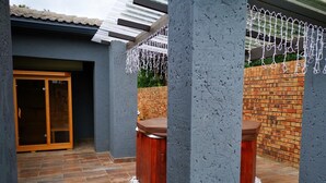 A patio area with a brick wall, a wooden bench, and a glass door leading to an interior space. - Green Olive Panorama (Bethlehem)
