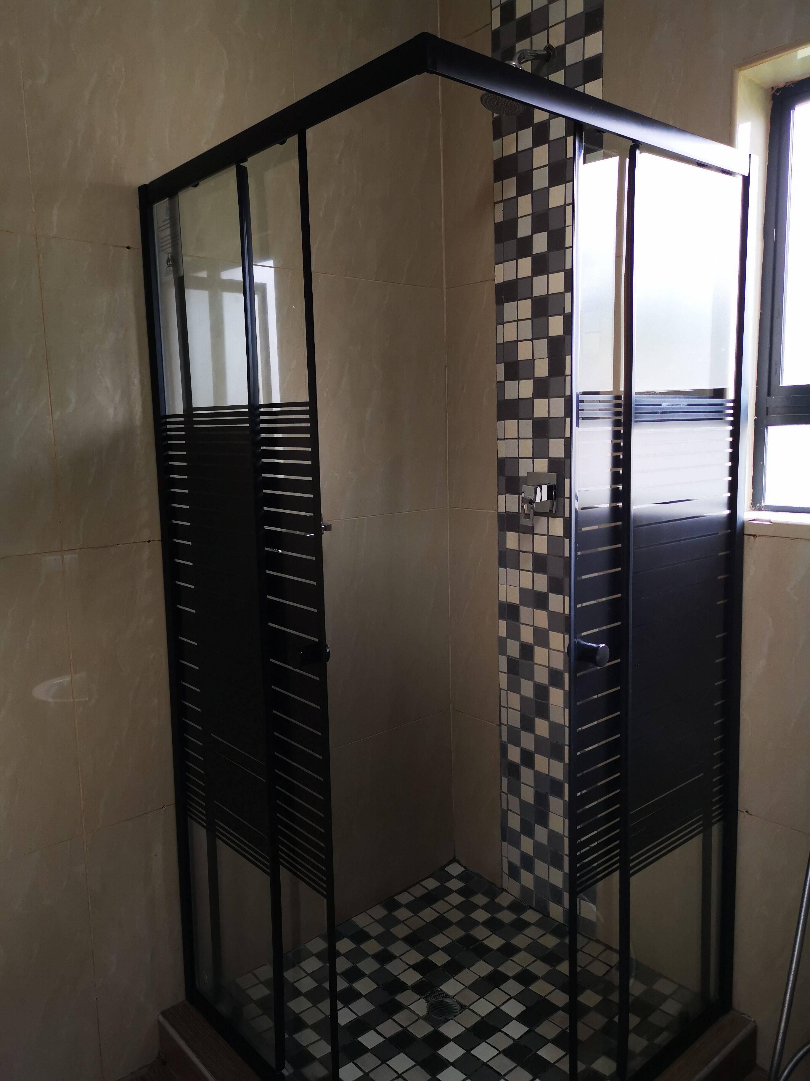 A corner shower enclosure with a checkered floor and a glass door.