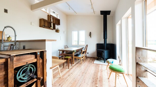 Une pièce spacieuse dotée d’un plancher en bois, d’une table à manger avec des chaises, d’une cheminée et d’une grande fenêtre laissant entrer la lumière naturelle.