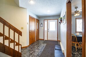 A hallway with a wooden staircase, a door, a ceiling fan, and a window. - Unwind at Quiet Snow - Mountain Retreat w/ Hot Tub (Davis)
