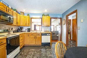 Cocina compacta con armarios de madera, estufa y lavavajillas.