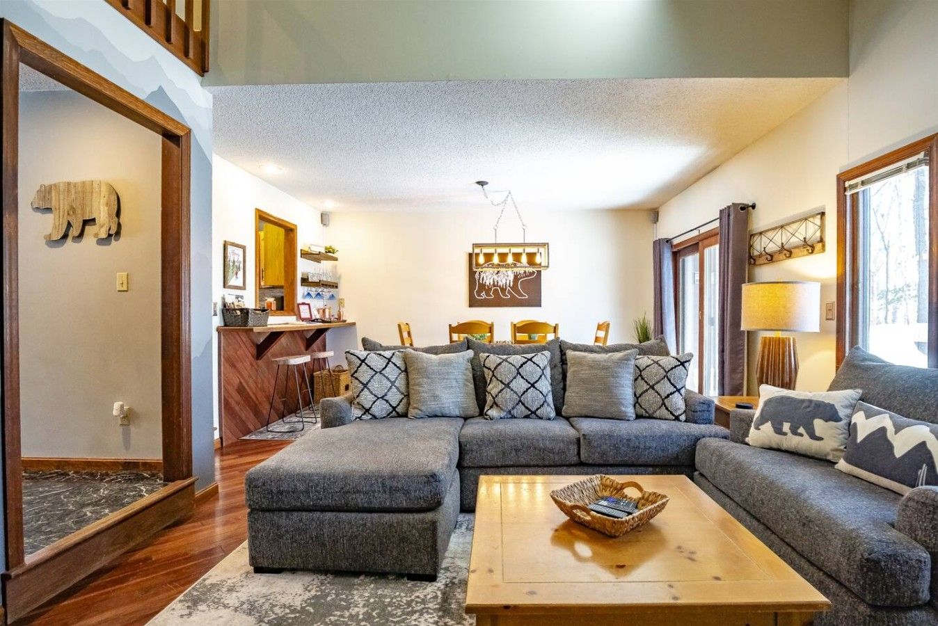 A cozy living room with a sectional sofa, a coffee table, and a kitchen area in the background.