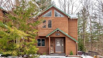 Une cabane en bois à deux étages, avec un toit vert, une porte d’entrée et une pancarte sur laquelle on peut lire : « Cabane tranquille ».