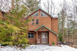 A two-story wooden cabin with a green roof, a front door, and a sign that reads 'Quiet Cabin.' - Unwind at Quiet Snow - Mountain Retreat w/ Hot Tub (Davis)