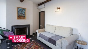 Un salon avec un canapé, une cheminée et un tableau accroché au mur.
